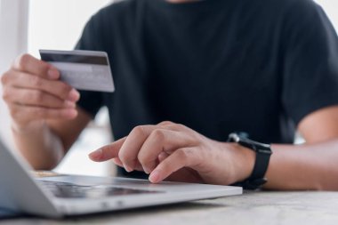 Çevrimiçi alışveriş e-ticaret ya da internet bankacılığı kavramı. Kredi kartı tutan ve dizüstü bilgisayar kullanan bir adam. İş finans ödemesi ve muhasebe.
