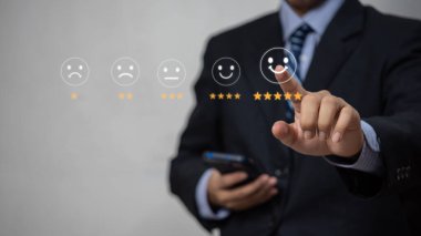 Müşteri hizmetleri ve memnuniyet geri bildirim konsepti değerlendirmesi yapmak için gülen yüz simgesine dokunan iş adamları.