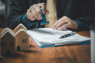 Buying and selling real estate or borrowing money, bank loans, approved investments.Businessman rubber stamp document and money coin on desk.