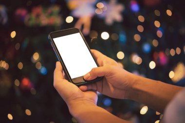 Erkek eller geceleri arka planda kapalı akıllı telefon kullanıyor. Telefon boş, beyaz ekran gibi..