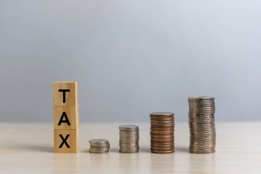 wood cube block TAX and coin money on desk. Business finance accounting income concept.