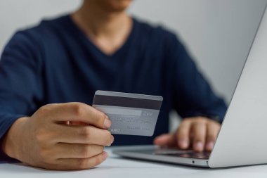 Adamın elinde kredi kartı var ve dizüstü bilgisayar kullanıyor. İş adamı ya da girişimci çalışıyor, e-ticaret, internet bankacılığı online alışveriş.