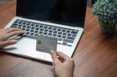 Kadın internetten laptop alışverişi yapıyor, kredi kartıyla ödüyor, ödeme yapıyor, bakiyeyi kontrol ediyor, internet bankacılığı hizmetlerine göz atıyor..