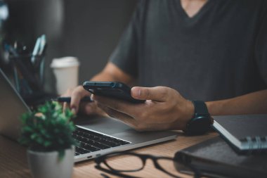 İşadamı dizüstü bilgisayarda çalışıyor ve masada cep telefonu kullanıyor..