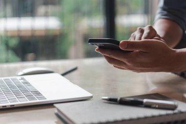 Adam cep telefonu kullanıyor ve dizüstü bilgisayar üzerinde çalışıyor. Eğitim ve teknoloji konsepti, öğrenci işleri, serbest çalışma.