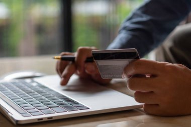 Adam elinde internet ödeme dizüstü bilgisayarı, çevrimiçi alışveriş dijital bankacılığı, iş dünyası finans teknolojisi kavramını kullanarak kredi kartı tutuyor..
