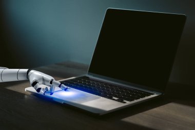 Robot parmağı dizüstü bilgisayarın düğme kontrolünü ve teknoloji yapay zeka ve otomasyon arayüzünü gösteriyor..