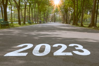 Yeni yıl 2023 ya da yeni yıl konsepti. Metin 2023 asfalt yolun ortasında gün batımında yazılmış..