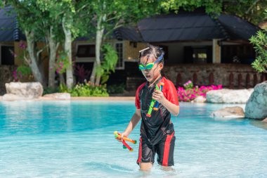 Mayo giymiş Asyalı küçük kız havuzda oyuncaklarla oynuyor ve eğleniyor..