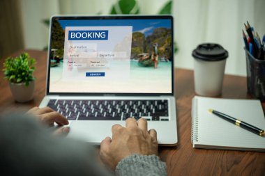 Dizüstü bilgisayarda bir kişi tarafından çevrimiçi rezervasyon platformu. Erkek, tatil gezileri için konaklama, otel ve havayolları ya da internet turları için web sitelerini kullanıyor.