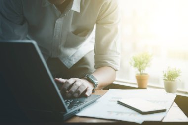 Adamın elleri masadaki dizüstü bilgisayarda yazarken, online ofiste bilgi aranıyor.