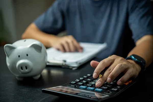 Adam kumbarayı tutan hesap makinesine basıyor. Yatırım, muhasebe, planlama, finansal ve bankacılık kavramı.