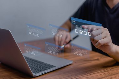 Adam anketi işaretli, anket formunu internetten seçiyor, test iş kontrol listesindeki soruları cevaplıyor ve anket formunu eğitim ve öğrenim için teknolojiyi kullanarak internetten dolduruyor..