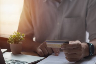 Kredi kartı tutan ve dizüstü bilgisayar kullanan eller. İnternetten alışveriş, internet bankacılığı. İş muhasebe finansal ve pazarlama kavramı.