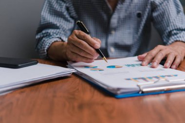 İş planlama, strateji, pazarlama ve mali raporları analiz eden işadamı Hand Holding Arşivi, raporları kontrol eden ve iş istatistiklerini gözden geçiren.