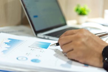 İş adamı elinde kalem belgeleri şeması ve grafik istatistik raporu yatırımı ve finansal bilgileri tutuyor..