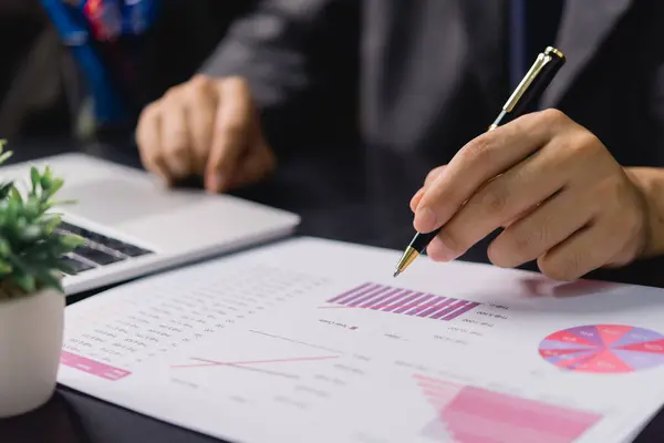 ペン文書を保持するビジネスマン手 図表分析図とグラフ統計レポート投資とデスク上の財務情報 ロイヤリティフリーのストック画像