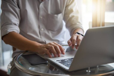 İnternette çalışan dizüstü bilgisayarı kullanan işadamı elleri, masadaki internet ve sosyal medyada bilgi teknolojisi verilerini araştırıyor.