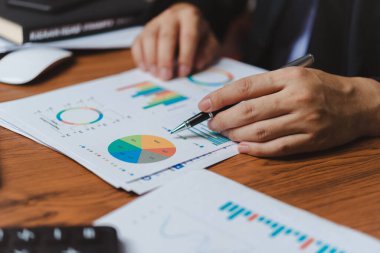 İşadamı çizelgeleri işaretlemek için bir kalem kullanıyor ve belgeleri ve grafikleri analiz ediyor. Ticari mali strateji ve veri analizi Pazarlama yenilikçiliği büyüme kavramını planlama.