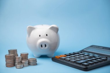 Finansal başarı hesap makinesi ve madeni parayla beyaz domuz kumbarası için para biriktiriyorum. Ticari mali planlama ve zenginlik yönetimi, muhasebe, vergi, sigorta kavramı.