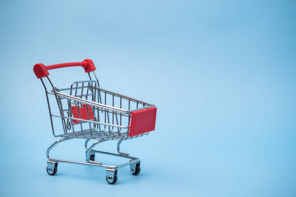 Корзина супермаркета на голубом фоне. Веб-сайты электронной коммерции, маркетинговые гарантии или контент, вращающийся вокруг розничной торговли, потребительских тенденций и торговых тенденций.