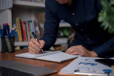 Ofisteki deftere kalem yazan erkek elleri. Öğrenme, eğitim ve çalışma. Hedefler, planlar, yapılacaklar ve dilekler listesi..