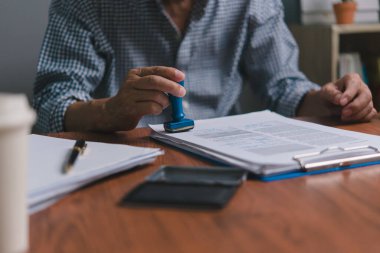 Hand man stamping documents notary public in office . Businessperson stamping approval of work finance banking or investment marketing documents on desk.	