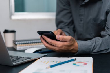 Ofiste çalışan cep telefonu ve dijital bilgisayar kullanan bir adam.