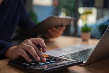 İş adamı, pazarlama sektöründeki mali, bankacılık ve vergi muhasebe belgelerine bakmak için hesap makinesi kullanır.