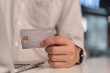 Kredi kartı tutan ve dizüstü bilgisayar kullanan bir iş adamı. İnternetten alışveriş ödemesi. Finans ve bankacılık kavramı. 