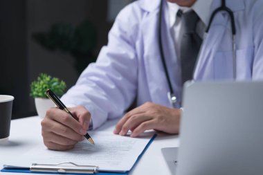 Doktor elinde bir kalem tutuyor ve muayeneler, hastaların tıbbi geçmişi hakkında notlar yazıyor. tıbbi reçete