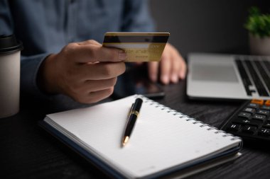 Kredi kartı tutan ve dizüstü bilgisayar kullanan bir iş adamı. İnternetten alışveriş ödemesi. Finans ve bankacılık kavramı.