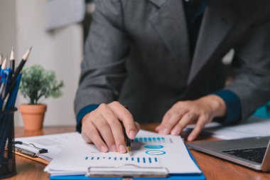 Businessman pointing chart analysis document and paperwork financial plan marketing with laptop on desk office.	