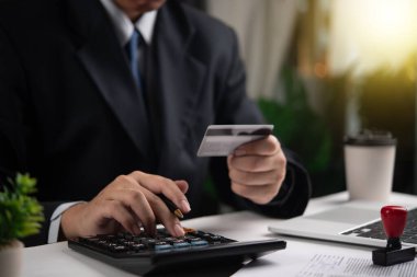 İş adamı hesap makinesi kullanıyor ve kredi kartı tutuyor. Finans, muhasebe, ödeme hesapları. Finansal hizmetler ve işletme yönetimi için uygundur.