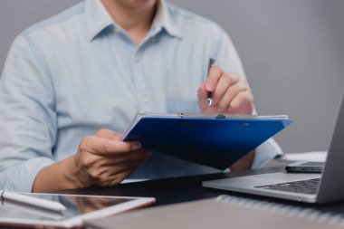 Ofis çalışanı panodaki belgeleri inceliyor, kalemle yazıyor. Profesyonel evrak işleri, şirket yönetimi. Görev yönetimi, verimlilik