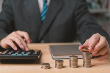 İşadamı masasında madeni paraları hesaplıyor, finans, tasarruf ve yatırımları sembolize ediyor. Ekonomik ve finansal hizmetlerin içeriği için ideal.