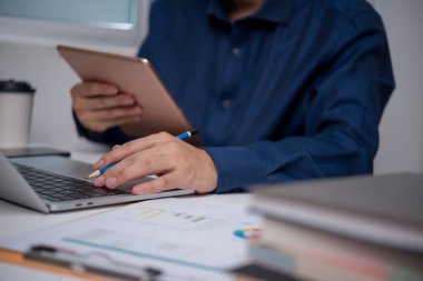İşadamı tablet ve dizüstü bilgisayarla birden fazla iş yapıyor, verileri analiz ediyor. Dijital çalışmayı, ofis verimliliğini temsil ediyor. Teknoloji ve şirket ortamları için ideal..