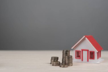 gayrımenkul ve servet yönetimi için tasarruf, emlak yatırımları ve finansal planlamayı temsil eden madeni para yığınlarının yanında ev modeli.