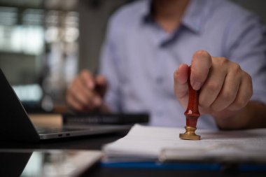Profesyonel bir iş adamı belge damgalıyor, otoriteyi ve doğrulamayı gösteriyor. Yasal, idari ve iş ortamlarına uygundur.