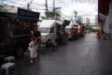 Gıda kamyonlarının bulanık görüntüsü, bir satıcının yanında aile ile birlikte bir caddeye dizilmiş, gelişigüzel görüntüler yakalıyorlar.,