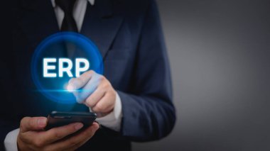 İşadamı dokunmatik ekranda dijital bir ERP simgesi ile etkileşime geçiyor, şirket kaynak planlaması ve iş teknolojisini temsil ediyor. İş yönetimi, bilişim hizmetleri ve yazılım çözümleri için ideal.
