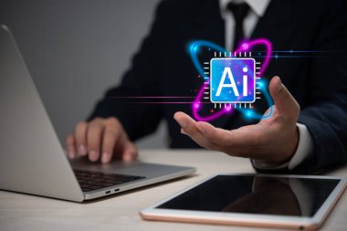 İş adamı elinde yapay zeka teknolojisini temsil eden bir dizüstü bilgisayar ve tabletle parlayan bir yapay zeka ikonu sunuyor..