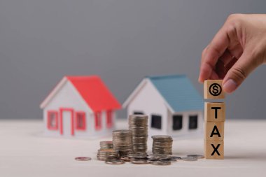 Emlak vergisi, yatırım ve finansal planlamayı temsil eden minyatür evler ve paraların yanında 