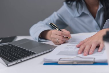 Ofis işlerini ve mesleki görevleri temsil eden bir iş kadını, bir dizüstü bilgisayarla bir masanın üzerine yazı yazıyor. İş, ofis ve idari amaçlar için mükemmel..