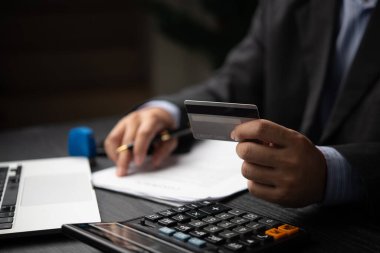 Kredi kartı tutan bir işadamı, mali işlem, ödeme ya da bankacılık işlemlerine hazırlanıyor. Kurumsal finans veya kişisel işlem kavramı.
