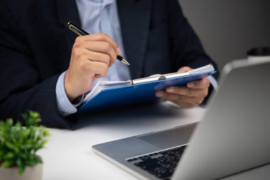 İşadamı, sözleşme imzalama ya da anlaşma analizini gösteren belgeleri kalemle inceliyor. Profesyonel iş ya da yasal ortam.