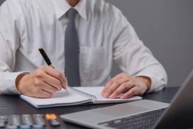 Elleri kalem ile ofiste deftere yazı yazan bir adam. Öğrenme, eğitim ve çalışma. Masaya hedefler, planlar ve dilek listesi yazıyor. işletme finans bankacılık veya yatırım pazarlama belgeleri