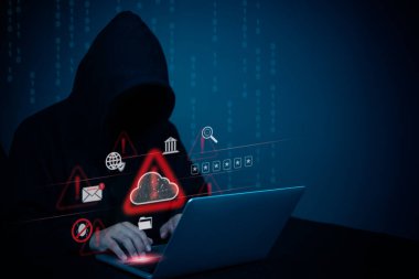 Bilgisayarında siber güvenlik uyarısı simgeli kukuletalı bir figür var. Hackleme tehditlerini, veri ihlallerini ve online suçları simgeliyor. Siber güvenlik kavramları için ideal.