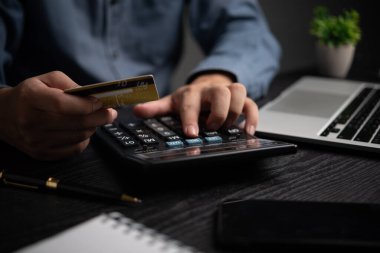 Hesap makinesi kullanırken kredi kartı tutan kişi, mali hesaplamayı, bütçeyi veya çevrimiçi ödemeyi sembolize ediyor. Fintech, bankacılık ve muhasebe için mükemmel.
