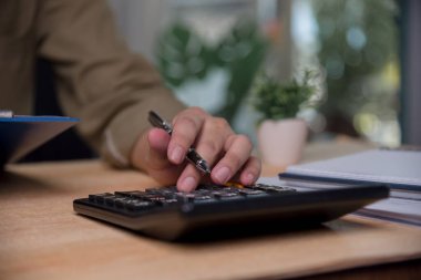 Erkek muhasebeci gelir vergisini hesaplayan bir hesap makinesine baskı yapıyor. Finansal, planlama ve yatırımları yönetme ve hedefe göre tasarruf yapma..